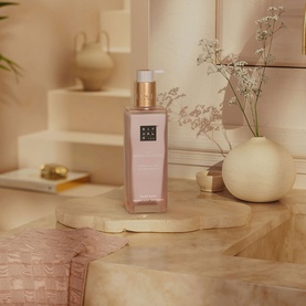 Rituals The Ritual of Sakura Hand Balm in a pink bottle with gold pump, styled on a wooden surface with neutral home d&eacute;cor