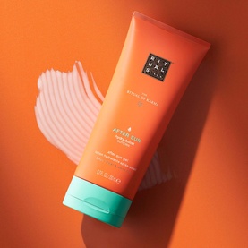 Rituals The Ritual of Karma After Sun Hydrating Lotion in orange tube with teal cap, shown with cream texture swatch on orange background.