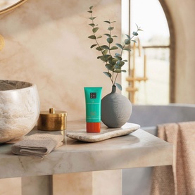 Rituals Ritual Sun Care Karma SPF50 tube on marble tray in a styled bathroom setting with vase and eucalyptus stems