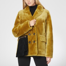 Model carrying Saint Laurent Grace Fringed Suede Small Hobo Bag in black with gold-tone hardware, styled with mustard faux fur coat