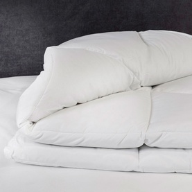 Snuggledown Hungarian Goose Down Natural Retreat Collection Duvet 13.5 Tog in white, folded and displayed on a bed with matching pillows