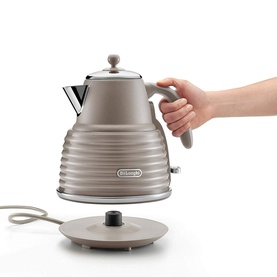 Delonghi Scolpito Kettle in beige with ribbed body design, shown being lifted from cordless base by a model's hand