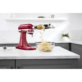 KitchenAid Spiralizer Attachment fitted to red stand mixer, spiralizing vegetables into a glass bowl on marble kitchen counter