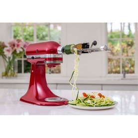 KitchenAid Spiralizer Attachment fitted to a red stand mixer, spiralizing courgette onto a white plate in a kitchen setting
