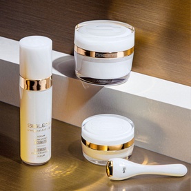Sisley Sisle&yuml;a L'Int&eacute;gral Anti-&Acirc;ge Firming Concentrated Serum in white and gold packaging, shown with two matching cream jars and a facial tool
