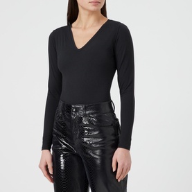 Model wearing Spanx Suit Yourself V-Neck Bodysuit in black, long sleeves, V-neckline, styled with black patent trousers
