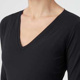 Model wearing Spanx Suit Yourself V-Neck Bodysuit in black, close-up showing V-neckline and long sleeves in smoothing fabric