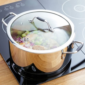 Stellar James Martin Casserole Pan 24cm in stainless steel with vented glass lid, shown on induction hob with vegetables cooking inside