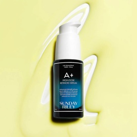 Sunday Riley A+ High-Dose Retinoid Serum in white pump bottle on yellow background with cream texture swirl