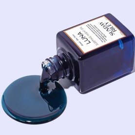 Sunday Riley Luna Sleeping Night Oil in deep teal-blue glass bottle tipped on its side with oil pooling beneath