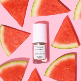 Sunday Riley Auto Correct eye cream in small white bottle, styled with fresh watermelon slices on a pink background.