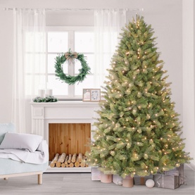 Puleo Prelit Kensington Fir Tree 7.5ft with warm clear lights, styled in a bright living room with fireplace and wreath