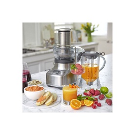 Sage The 3X Bluicer Pro Blender in brushed silver, shown with fresh fruit, juice glasses, and a pitcher in a kitchen setting