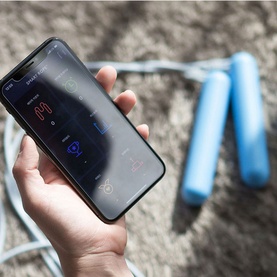 Tangram SmartRope Rookie Blue skipping rope with blue handles, shown alongside a smartphone displaying the companion app