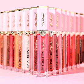 Too Faced Lip Injection Power Plumping Lip Gloss in Paid Off, displayed among a row of glosses in varied pink and coral shades