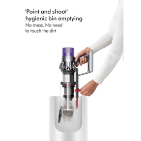 Dyson Home V10 Cyclone Absolute Cordless Stick Vacuum Cleaner demonstrating hygienic point-and-shoot bin emptying into white docking bin