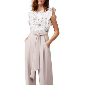 Model wearing Phase Eight Victoriana Printed Jumpsuit in cream, featuring floral print ruffle top and wide-leg belted trousers with pleat front