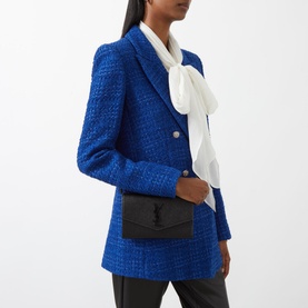 Model carrying Saint Laurent Uptown Embossed Leather Chain Wallet in black with gold-tone chain strap, styled with blue tweed blazer and white scarf