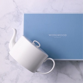 Wedgwood Gio Teapot in white fine bone china with geometric embossed detail, shown beside blue Wedgwood gift box on marble surface