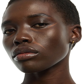 Model with YVES SAINT LAURENT Touche &Eacute;clat concealer, close-up showing luminous, even complexion and defined eyes with small gold hoop earring