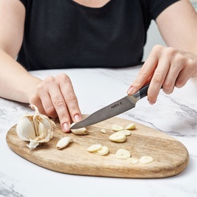 Zyliss Comfort Pro Paring Knife 11cm in stainless steel, used to slice garlic on a wooden chopping board