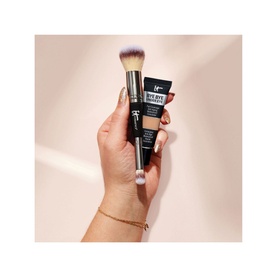 Model with IT COSMETICS Bye Bye Under Eye Concealer held alongside a large makeup brush, shown in hand