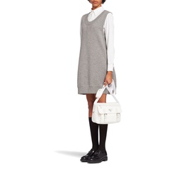 Model carrying Prada Accessories Re-Nylon Shoulder Bag in white with gold hardware, styled with grey pinafore dress, white shirt and black loafers
