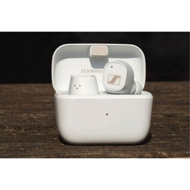 Sennheiser CX Plus True Wireless Earbuds in white, shown in open charging case on dark wood surface