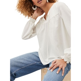 Model wearing Phase Eight Viviana Tie Neck Jersey Blouse in cream with frill cuffs and relaxed fit, styled with blue jeans