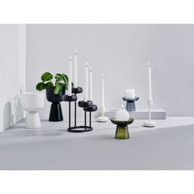 Iittala Nappula Pillar Candle Holder 107mm in moss green glass, styled with matching white and black candleholders on a pale surface