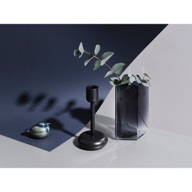Iittala Nappula Candle Holder 107mm in dark grey, styled with a smoked glass vase holding eucalyptus stems and a small ceramic dish