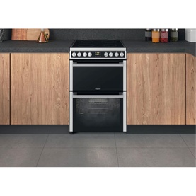 Hotpoint Silver Electric Freestanding Double Cooker 60cm with ceramic hob and double oven, set in a wood-effect fitted kitchen