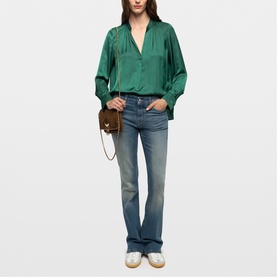Model wearing Zadig Tink Satin Shirt in green with notched neckline and long sleeves, styled with blue bootcut jeans and a small brown bag.