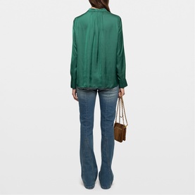 Model wearing Zadig Tink Satin Shirt in green with long sleeves, styled with blue flare jeans and carrying a small brown chain bag.