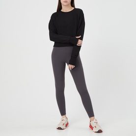 Model wearing Sweaty Betty After Class Cropped Sweatshirt in black, styled with dark grey leggings and multicolour trainers