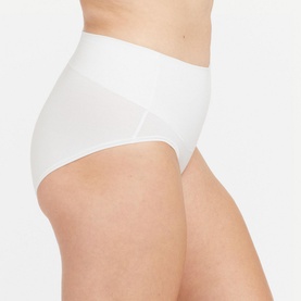 Model wearing Spanx Cotton Comfort Light Control Briefs in White, high-waist brief with smooth double-layer waistband and no-dig leg opening