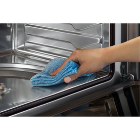 Fisher & Paykel 37L 900W Built-in Combination Microwave stainless steel interior being wiped clean with a blue microfibre cloth