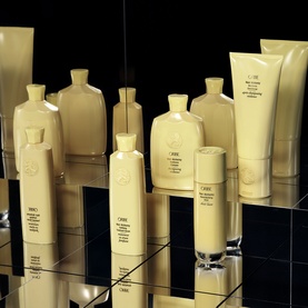 Oribe Hair Alchemy Resilience Conditioner shown alongside matching haircare collection in cream and gold packaging on mirrored surface