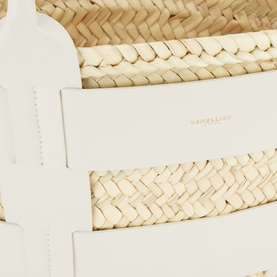 DeMellier Miniature Santorini Basket Bag in cream, close-up of woven palm leaf body with white leather trim and embossed logo detail