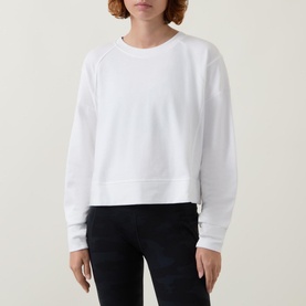 Model wearing Sweaty Betty After Class Cropped Sweatshirt in white, styled with dark slim-fit jeans