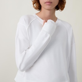 Model wearing Sweaty Betty After Class Cropped Sweatshirt in white, showing long raglan sleeves and relaxed neckline detail