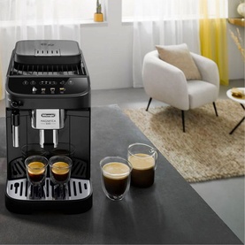 DeLonghi Magnifica Evo Automatic Coffee Maker in black, dispensing espresso into two glass cups, styled in a modern living room setting