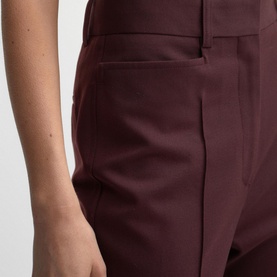 Model wearing Reiss Flora Flared Trousers in pink, showing mid-rise waistband, belt loops, and side pocket detail