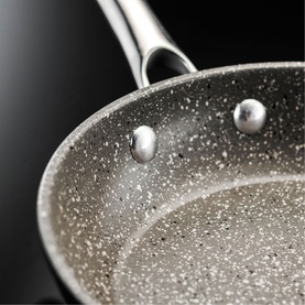 Stellar Rocktanium Non-Stick Frying Pan in grey, close-up of speckled PFOA-free surface with riveted stainless steel handle detail