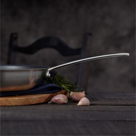 Stellar Eclipse Non-Stick Frying Pan 28cm in stainless steel, shown on wooden board with garlic and dill, dark moody background