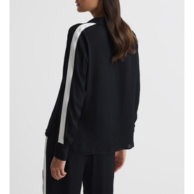 Model wearing Reiss Millie Side Stripe Shirt in blue, back view, with white contrast side stripe and long sleeves, paired with matching blue trousers