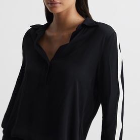 Model wearing Reiss Millie Side Stripe Shirt in blue, showing V-neck collar, long sleeves and contrast white side stripe detail