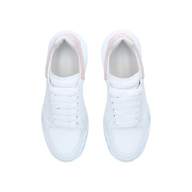 Alexander McQueen Oversized Court Trainers in white leather, low-top lace-up with pink heel tab and chunky textured rubber sole, overhead view
