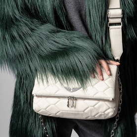 Model carrying Zadig Rocky XL Mat Scale Bag in white quilted lamb leather with silver chain strap and wings emblem, styled with green faux fur coat