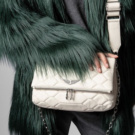 Model carrying Zadig Rocky XL Mat Scale Bag in white quilted lamb leather, silver chain strap and wings emblem, styled with green fur coat
